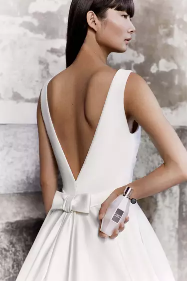 Model wearing white dress holding Flowerbomb Mariage Limited Edition Eau de Parfum