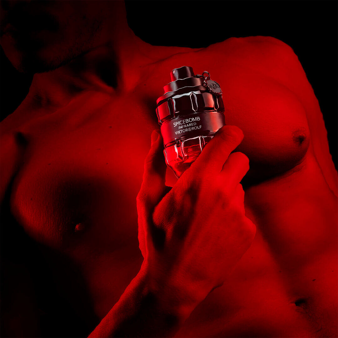 Red colored man's chest holding a bottle of Spicebomb Infrared